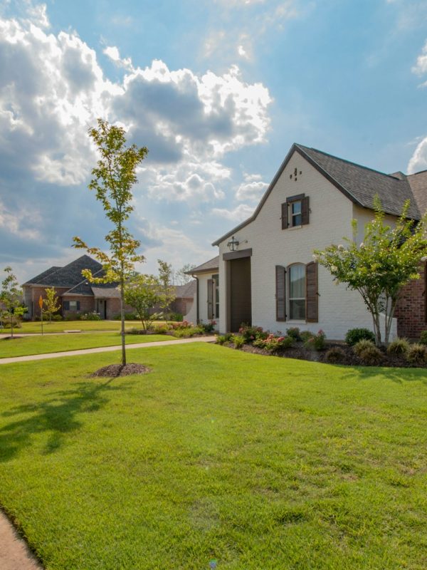white and brown house near green grass field under white clouds and blue sky during daytime